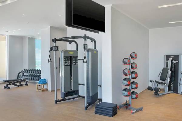 Fitnessbereich im Hilton Hurghada Plaza Hotel mit modernen Trainingsgeräten und Blick auf den Außenbereich.