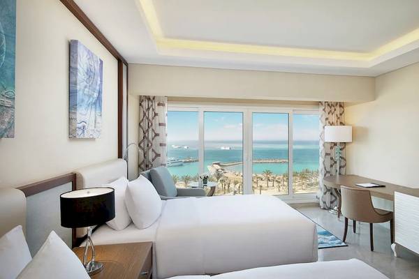 Hotelzimmer im Hilton Hurghada Plaza mit Meerblick, zwei Betten, Schreibtisch und Fernseher.
