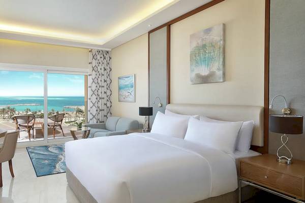 Hotelzimmer im Hilton Hurghada Plaza mit Meerblick, inklusive Bett, Schreibtisch und Terrasse.