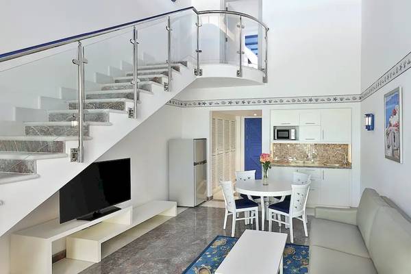 Innenraum des Hilton Hurghada Plaza mit Wohnzimmer, Couch, Tisch, Fernseher und Treppe.