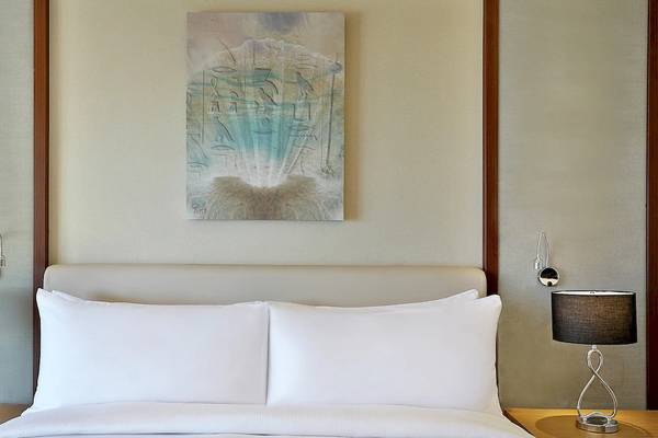 Schlafzimmer im Hilton Hurghada Plaza mit zwei Lampen und einem gerahmten Gemälde an der Wand.
