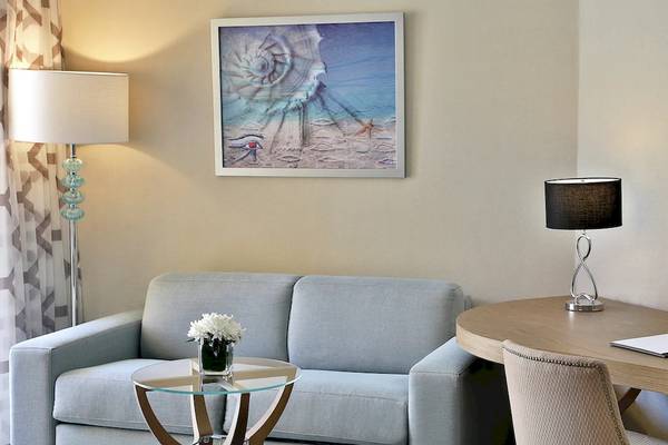 Ein elegantes Hotelzimmer mit Sofa, Tisch, Schreibtisch und Kunstwerk an der Wand im Hilton Hurghada Plaza.
