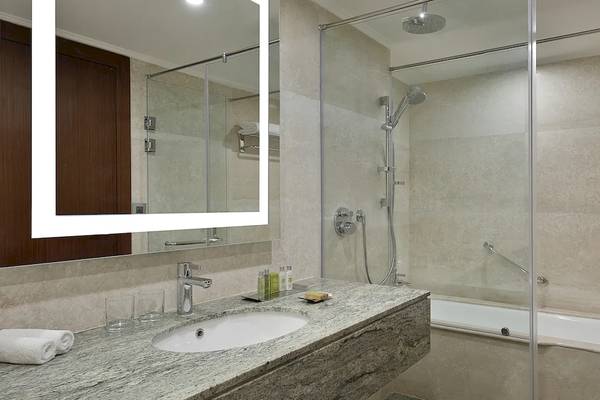 Das Badezimmer im Hilton Hurghada Plaza mit einer Dusche, Badewanne und Spiegel.