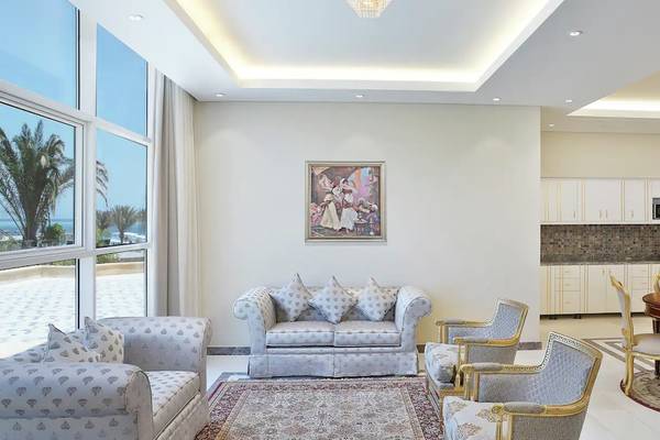 Wohnzimmer des Hilton Hurghada Plaza Hotels mit grauem Sofa, Esstisch und rote Rosen in einer Vase.