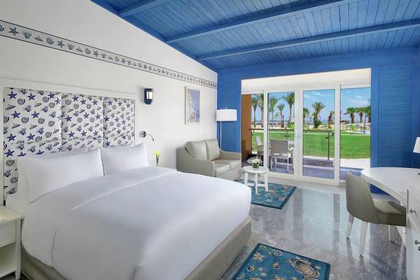 Innenansicht eines Schlafzimmers im Hilton Hurghada Plaza Hotel mit blauem Dach, weißen Wänden und Meeresdekor.