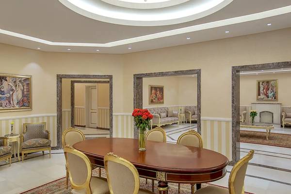 Ein eleganter Speisesaal im Hilton Hurghada Plaza mit einem runden Tisch, goldenen Stühlen und Wandgemälden.