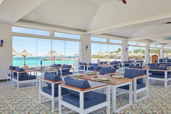 Innenansicht des Restaurants im Hilton Hurghada Plaza mit Blick auf das Meer und viele blaue Möbel.