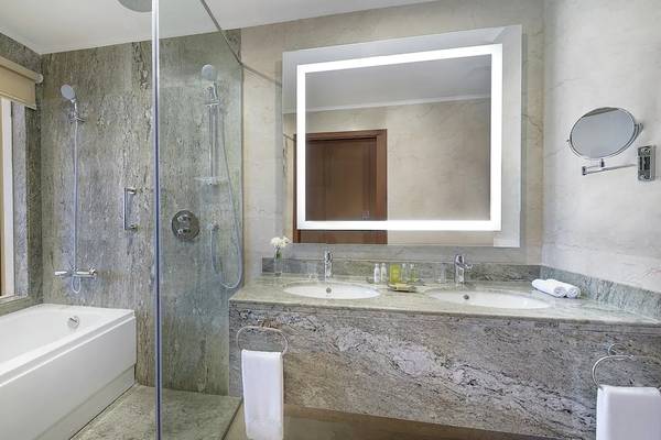 Badezimmer im Hilton Hurghada Plaza mit Badewanne, Dusche, Waschbecken und Spiegel.