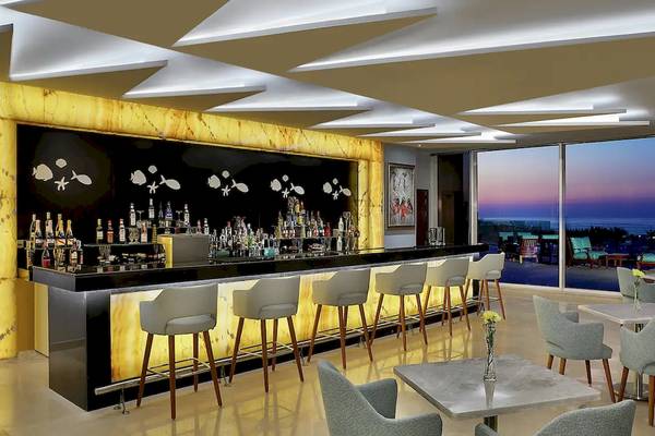 Innenansicht der Bar im Hilton Hurghada Plaza Hotel mit Bartheke, Stühlen und Tischen sowie Blick auf den Ozean.