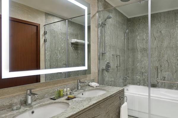 Badezimmer im Hilton Hurghada Plaza mit zwei Waschbecken, einer Badewanne und einer Glasdusche.
