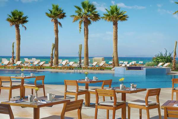 Außenbereich des Hilton Hurghada Plaza mit Swimmingpool, Liegestühlen und Palmen.