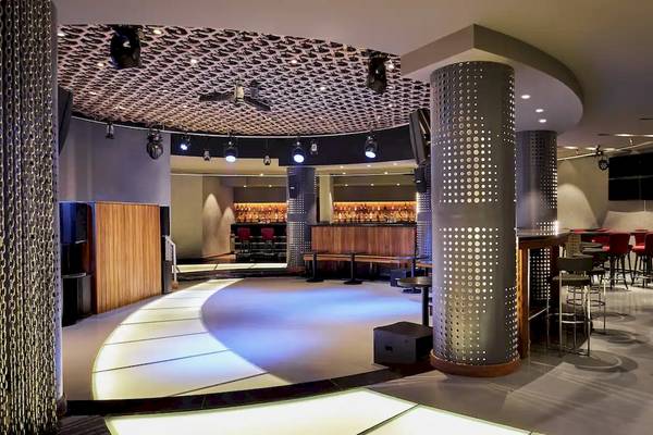 Innenansicht der Bar im Hilton Hurghada Plaza mit Rundum-Sitzbereich, Säulen und moderner Beleuchtung.