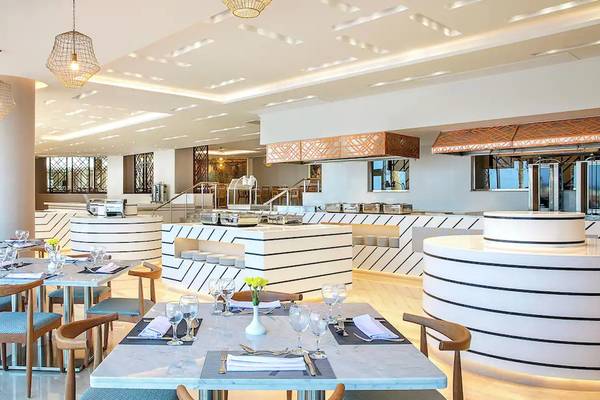 Innenansicht des Restaurants im Hilton Hurghada Plaza mit modernen Möbeln und Tischarrangements.