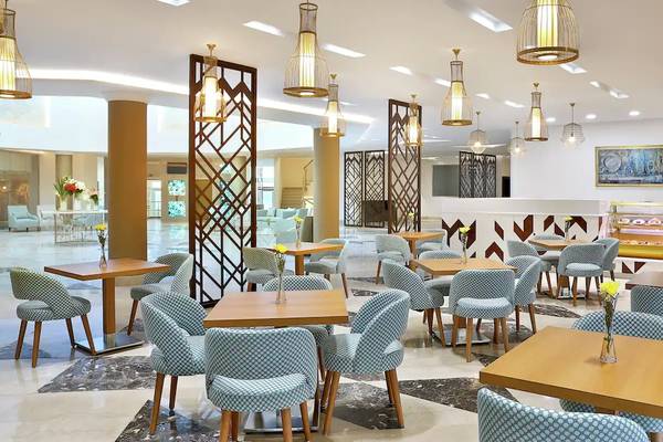 Innenansicht des Restaurants im Hilton Hurghada Plaza Hotel mit Tischen, Stühlen und dekorativen Lampen.