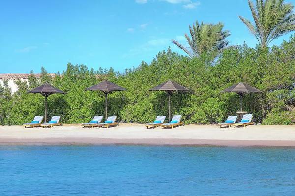 Strand des Hilton Hurghada Plaza mit Sonnenliegen und Sonnenschirmen.