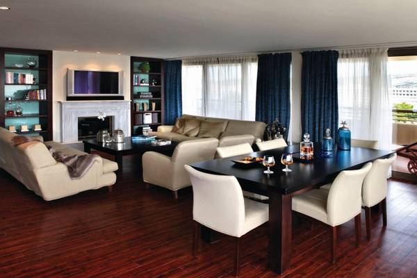 Wohnzimmer des Porto Carras Meliton Hotels mit hellem Holzboden, Sofas, Esstisch, Fernseher und Kamin.