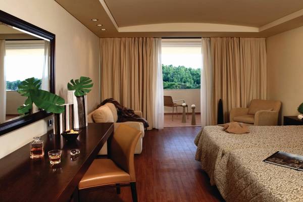 Innenansicht eines Hotelzimmers im Porto Carras Meliton, mit Doppelbett, Sessel, Schreibtisch und Terrassentür.