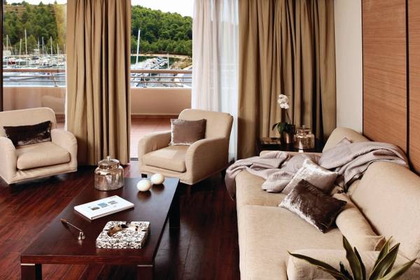 Wohnzimmer des Porto Carras Meliton Hotels mit Seeblick, zwei Sesseln, einem Tisch und einer Couch.