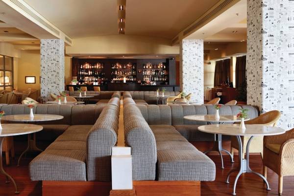 Loungebereich des Porto Carras Meliton Hotels mit Tischen, Stühlen und einer Bar.