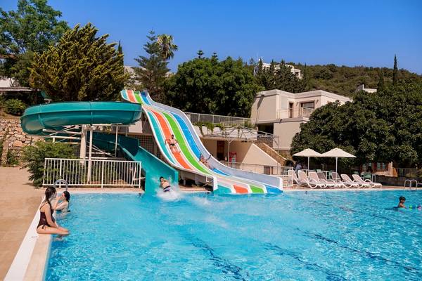 Wasserrutsche im Schwimmbad des Duja Bodrum Hotels mit Personen, die darauf rutschen und spielen.