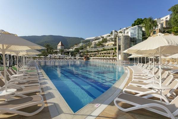 Außenpoolbereich des Duja Bodrum Hotels mit vielen Liegestühlen und Sonnenschirmen.
