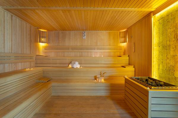 Innenansicht einer Sauna im Duja Bodrum Hotel mit Holzbänken, gestapelten Handtüchern und einer gelben Wand.