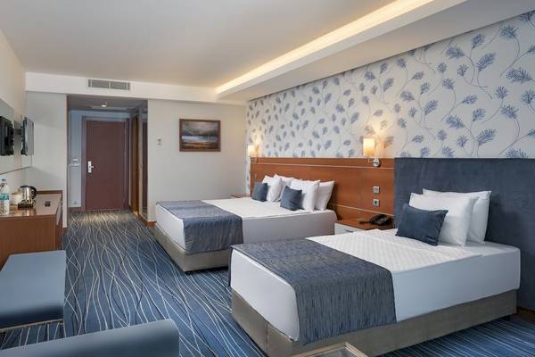Doppelzimmer im Duja Bodrum Hotel mit zwei Betten, Dekor und Fernseher an der Wand.