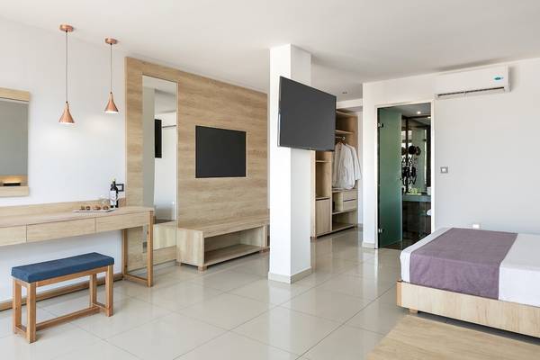 Schlafzimmer im CHC Galini Palace Hotel mit Doppelbett, Fernseher und beleuchteten Lampen.