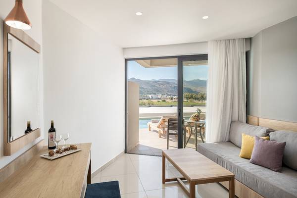 Wohnzimmer des CHC Galini Palast mit Zugang zur Terrasse, zeigt ein modernes Interieur mit einem offenen Bereich, der zu einer Poolterrasse führt.