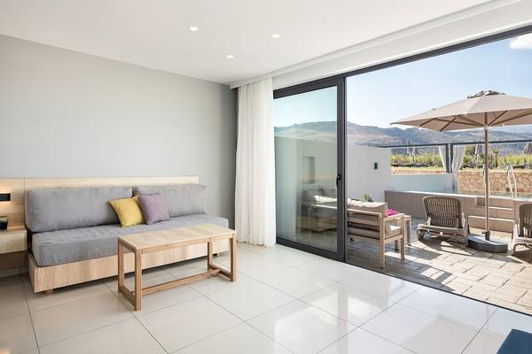 Innenbereich des CHC Galini Palace mit Sofa, Tisch und Terrassenzugang