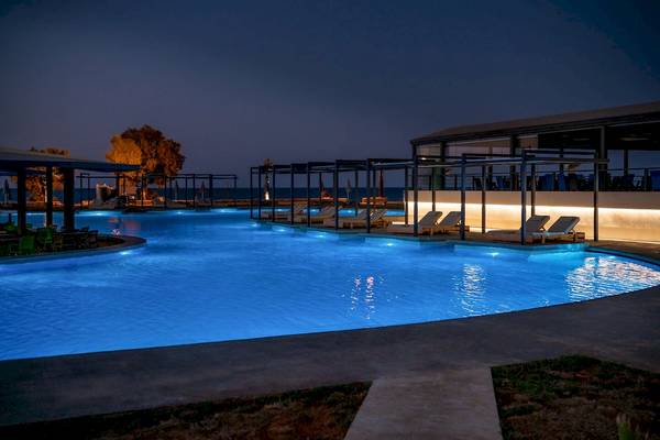 Pool des CHC Galini Palace bei Nacht mit beleuchteten Loungeliegen und Meer im Hintergrund.