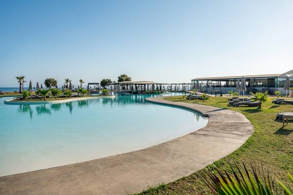 Außenpoolbereich des CHC Galini Palace Hotels am Meer mit Sonnenliegen und Sonnenschirmen