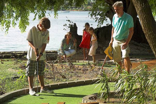 Familie spielt Minigolf im Maritim Resort & Spa Mauritius mit Blick auf den Ozean