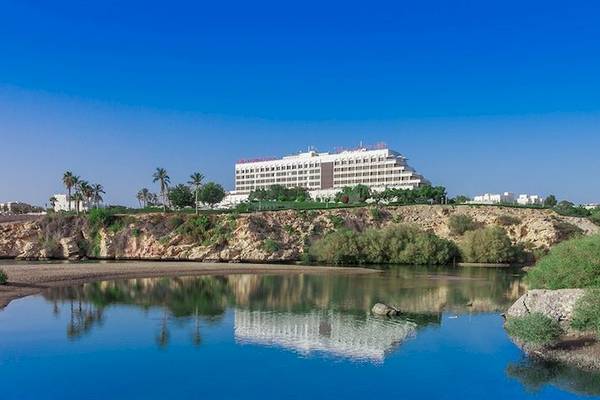 Außenansicht des Crowne Plaza Muscat Hotels mit Gebäuden und Landschaft im Hintergrund