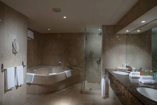 Badezimmer mit Whirlpool und Dusche im Crowne Plaza Muscat Hotel.