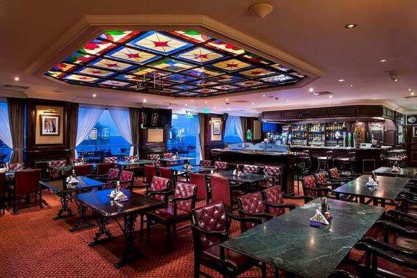 Innenansicht des Crowne Plaza Muscat Restaurants mit farbiger Glasdecke, roten Stühlen und Tischen.