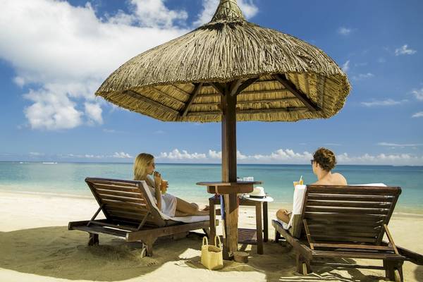 Paar unter einem Sonnenschirm auf dem Strand des Maritim Resort & Spa Mauritius