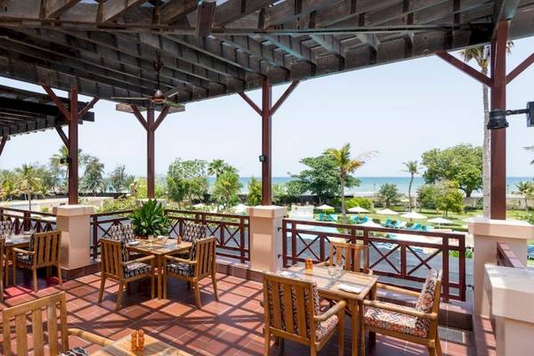 Terrasse des InterContinental Muscat mit Blick auf das Meer und eine Reihe von Tischen und Stühlen.