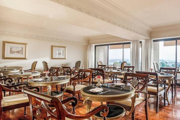 Innenbereich des Restaurants im Intercontinental Muscat, an IHG Hotel mit runden Tischen, Stühlen und großen Fenstern.