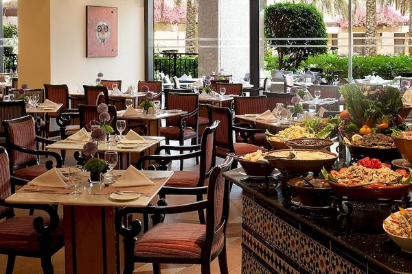 Restaurant des InterContinental Muscat mit vielen gedeckten Tischen und Büfett mit verschiedenen Gerichten.