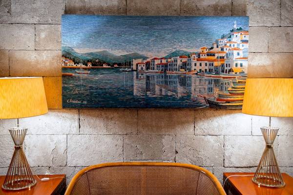 Ein Gemälde im Mittelmeer-Hotel auf Rhodos zeigt eine Stadt am Wasser mit Booten und Gebäuden.