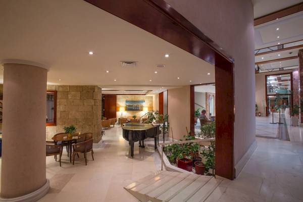 Innenansicht des Foyers im Mediterranean Hotel auf Rhodos mit Klavier, Tischen und Stühlen.