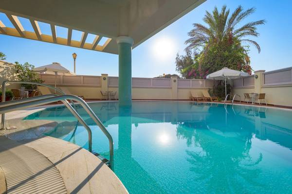 Poolbereich des Mediterranean Hotel auf Rhodos mit Sonnenliegen und Schirmen.