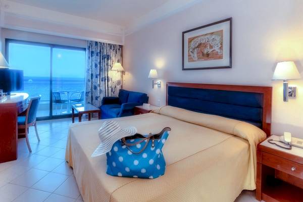 Zimmer im Mediterranean Hotel auf Rhodos mit Blick auf das Meer, einem Bett, einem Schreibtisch und einem Balkon.