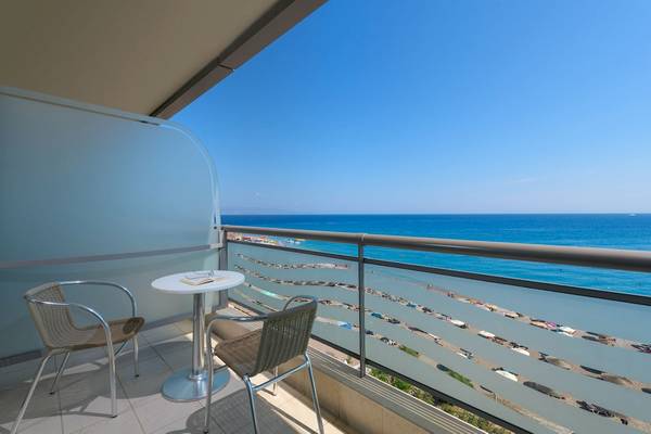 Ein Balkon mit Meerblick im Mediterranean Hotel auf Rhodos mit zwei Stühlen und einem Tisch.