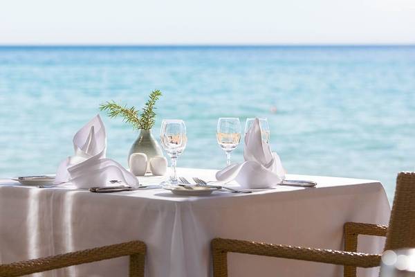 Tisch am Strand mit Blick auf das Meer, gedeckt für ein romantisches Abendessen.