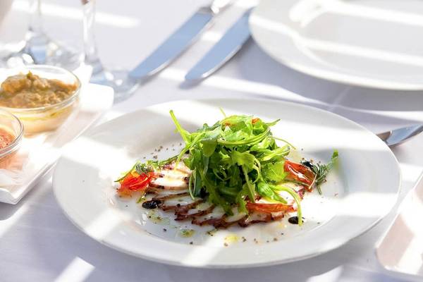 Gedeckter Tisch im Kernos Beach Hotel & Bungalows mit einem Teller Salat und Beilagen.
