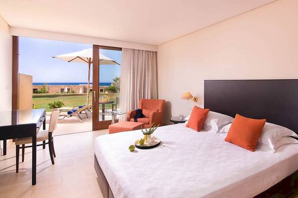 Zimmer im Kernos Beach Hotel & Bungalows mit Blick auf das Meer, einem großen Bett und einem Balkon.
