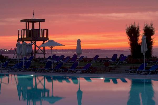 Abendstimmung am Pool des Kernos Beach Hotel & Bungalows mit Lounge-Stühlen und Sonnenschirmen.