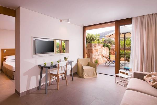 Innenansicht eines Zimmers im Kernos Beach Hotel & Bungalows mit Bett, Schreibtisch und Fernseher.